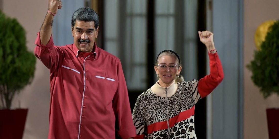 Presiden Venezuela Nicolas Maduro bersama istrinya, Cilia Flores, melambaikan tangan di luar Istana Kepresidenan Miraflores saat menghadiri aksi dukungan terhadap hasil pemilihan presiden di Caracas, 7 Agustus 2024. (Photo by Yuri CORTEZ / AFP)